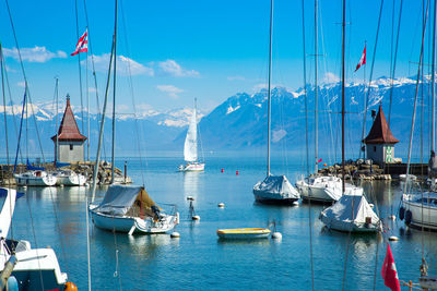 Sailboats moored in sea against sky