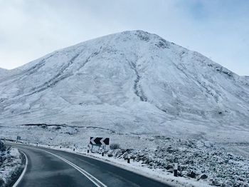 Road by snowcapped mountain against sky