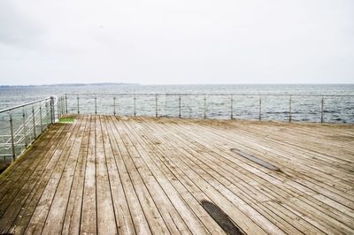 Wooden boardwalk on beach against sky