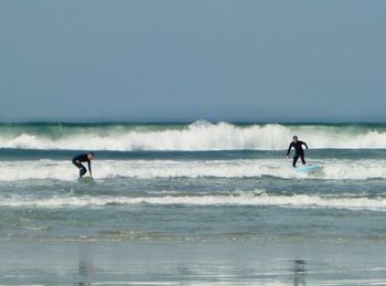 People surfing in sea against sky