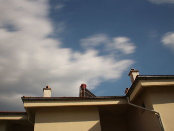 Low angle view of bird perching on building against sky