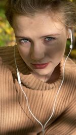 Smiling girl phone headphones forest beige sweater messaages music