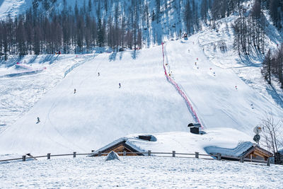 Snow covered house against trees on mountain during winter in alps