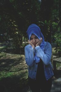 Young woman with hands on cheek standing on field