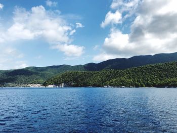 Scenic view of sea by mountains against sky