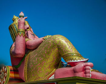 Low angle view of woman sitting on temple against clear sky