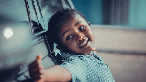 Smiling girl standing by car outdoors