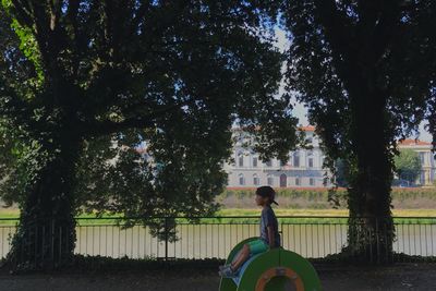 Boy playing on slide by trees at park in city