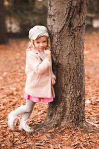 Cute girl leaning on tree trunk in park