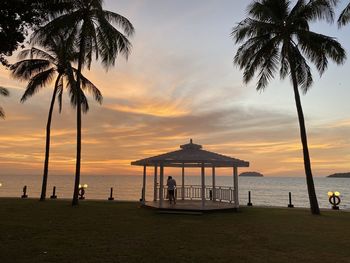 Silhouette palm trees on beach against sky during sunset