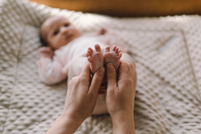 Mum making baby massage, mother massaging infant bare foot, preventive massage for newborn.