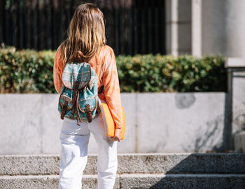 Rear view of woman standing against wall in city