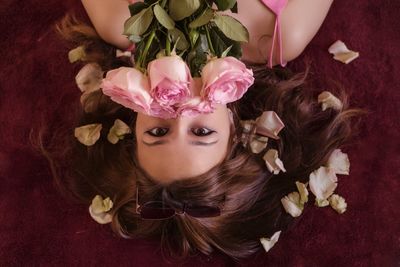 Close-up portrait of woman with pink roses lying on bed