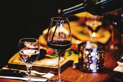 Drinking water by bottle pouring wine in glass on table