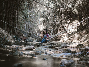 Smiling mother sitting on hammock in stream