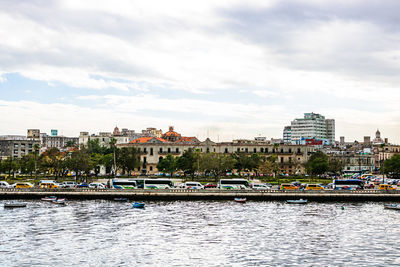 City at waterfront against cloudy sky