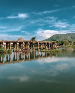 Arch bridge over water against cloudy sky