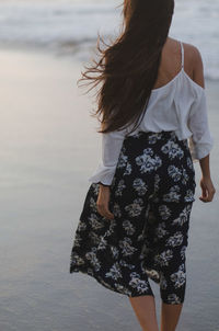 Rear view of woman standing at beach