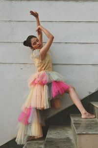 Full length of woman standing against pink wall