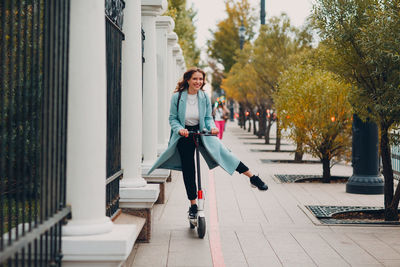 Full length of woman standing on push scooter