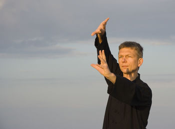 Mature man practicing tai chi at beach against clear blue sky