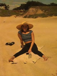 Full length of young woman sitting on sand