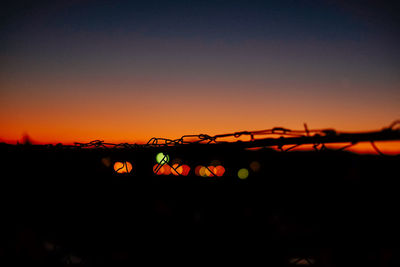 Silhouette of illuminated city against clear sky at sunset