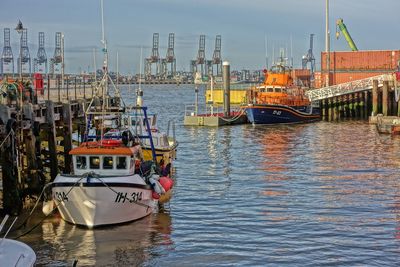 Boats moored at harbor against sky