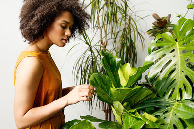 Side view of young woman looking at plant