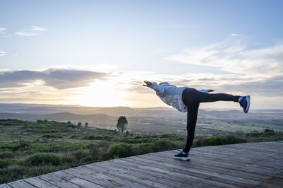 Rear view of woman standing on mountain against sky