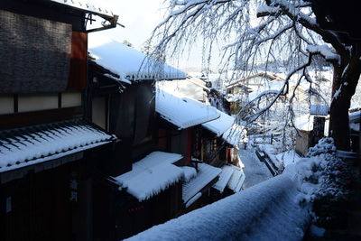 Snow covered houses by trees and buildings