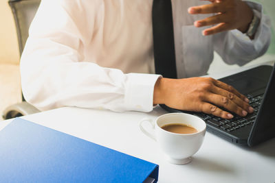 Midsection of businessman using laptop on desk