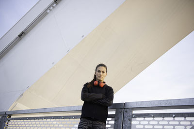 Portrait of young woman standing against wall