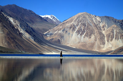 Scenic view of lake and mountains against blue sky