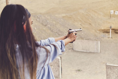 Woman releasing stress, instructor helping woman with gun