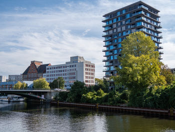 Buildings by river against sky