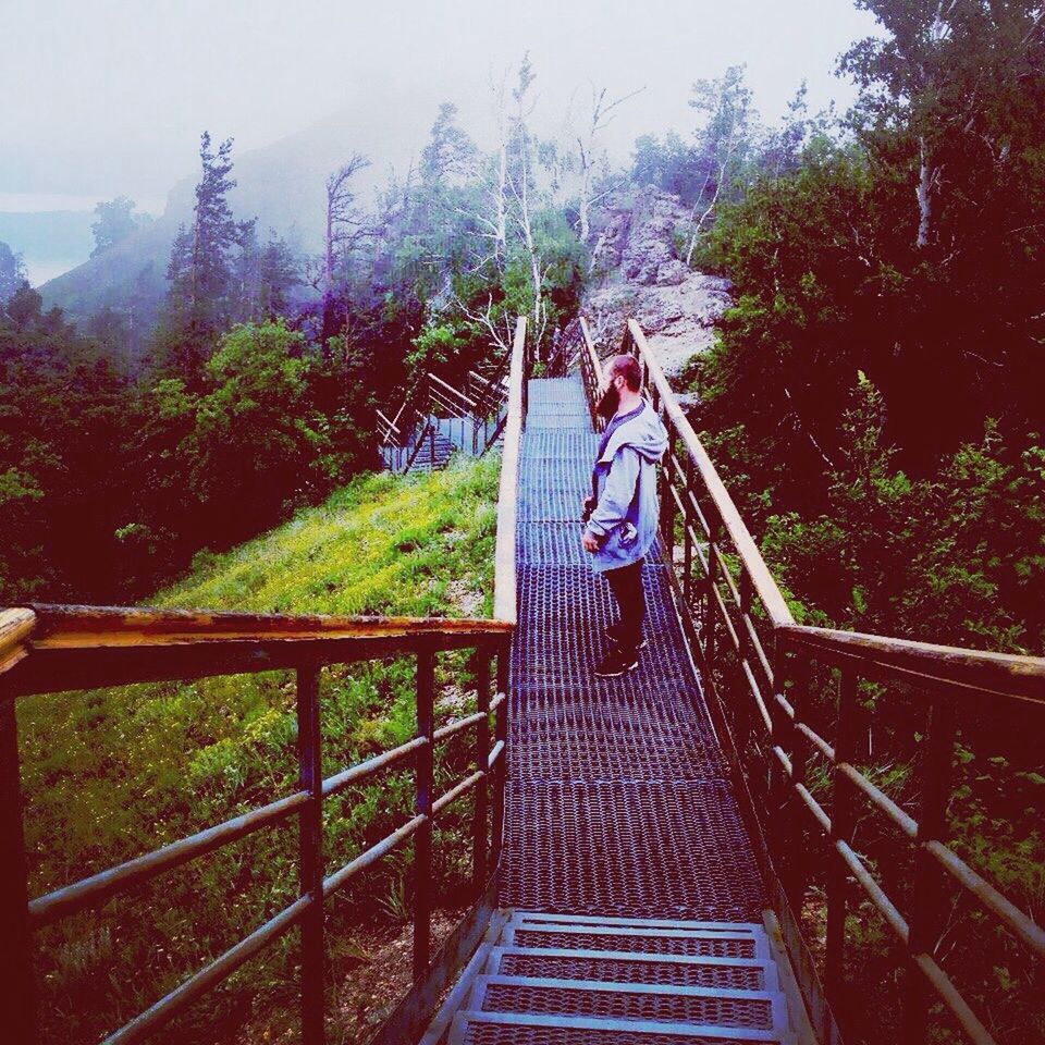 WOMAN STANDING BY FOOTBRIDGE