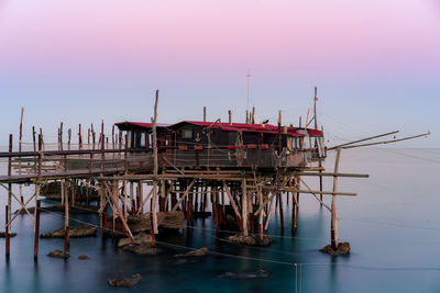 Cranes in sea against clear sky during sunset