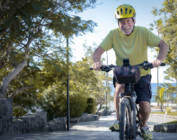 Portrait of smiling senior man riding bicycle outdoors