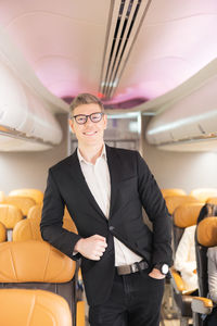 In the plane, there is a young passenger. portrait of a man standing in an airplane aisle