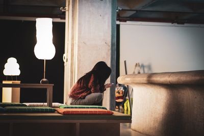 Side view of woman sitting in corridor