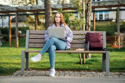 Choosing a university, college. female college student with books and laptop outdoors. redhead