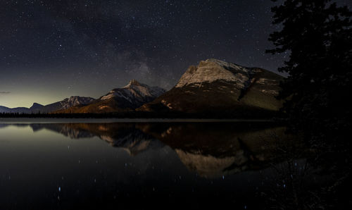 Reflection of mountain in lake against sky at night