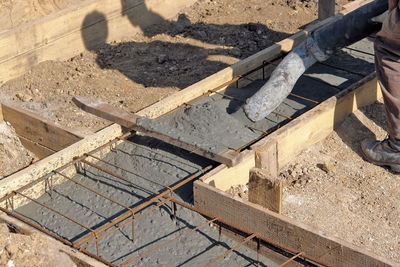 Construction worker filling house foundation with concrete mix