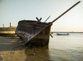 Abandoned boat on beach against clear sky