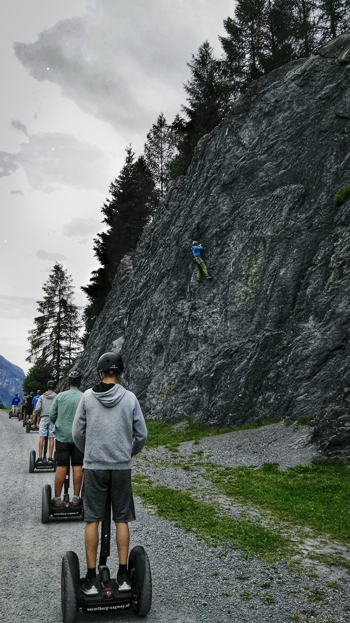 rear view, plant, men, lifestyles, tree, real people, day, nature, people, leisure activity, transportation, full length, activity, land vehicle, two people, mountain, sky, riding, mode of transportation, ride, outdoors