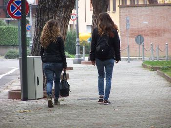 Rear view of man walking on sidewalk in city