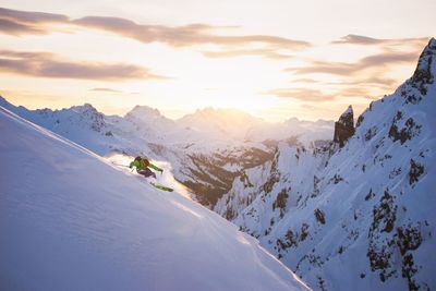 Man skiing on snowcapped mountain during sunset