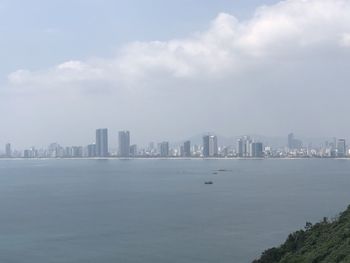 Sea by buildings in city against sky