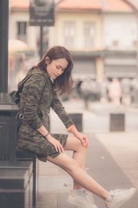 Full length of young woman sitting outdoors